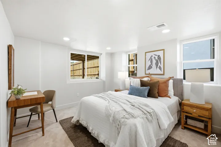 Recessed ceiling lighting, multiple egress windows, light neutral wall color, and carpeted flooring