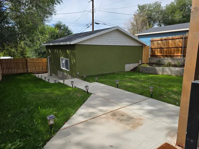 Dedicated structure with stucco exterior, concrete pathway, and landscaped retaining wall