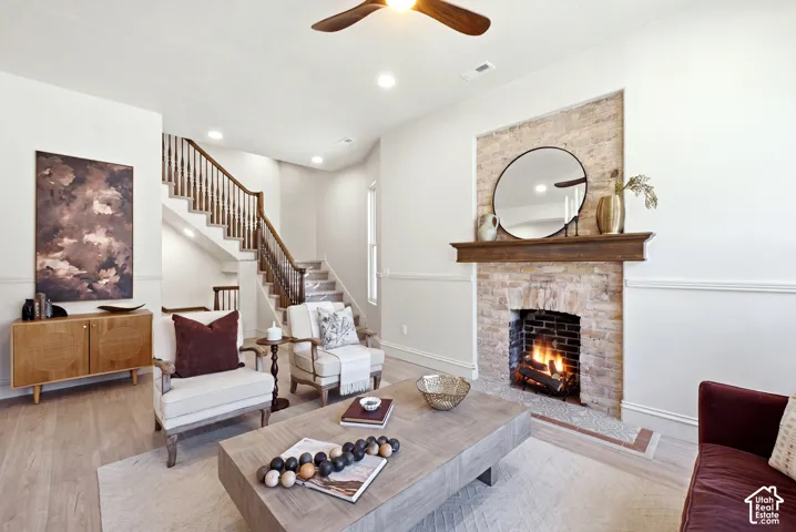 Exposed brick fireplace with a wood-finish mantel, wood-finish flooring, recessed lighting, and a wood-finish ceiling fan