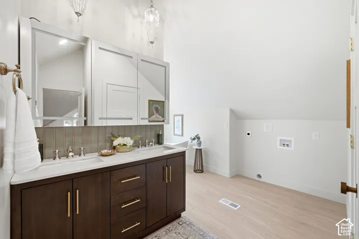 Dual sink vanity with dark wood-finish cabinetry, light countertop, and integrated sinks