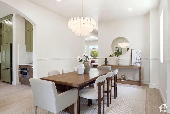 Open-concept dining area featuring wood-finish flooring, recessed lighting, and a decorative chandelier