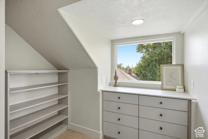 Built-in shelving and dresser cabinetry with black hardware, recessed ceiling lighting, and a window framing mature trees