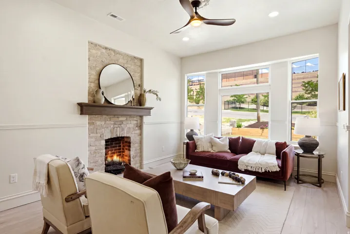 Stone-clad fireplace with wood mantel, large multi-pane windows, recessed lighting, and wood-finish flooring