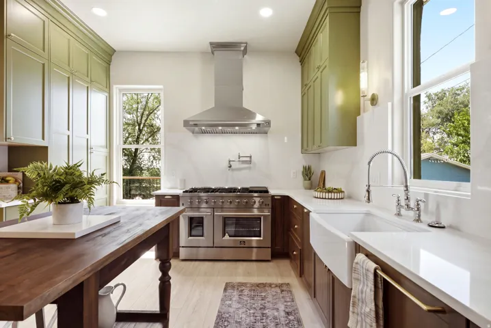 Gourmet kitchen featuring a professional-grade range with a stainless steel hood, an integrated pot filler, a farmhouse sink, and dual-tone cabinetry with extensive storage
