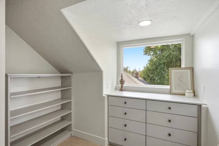 Built-in shelving and dresser cabinetry with black hardware, recessed ceiling lighting, and a window framing mature trees