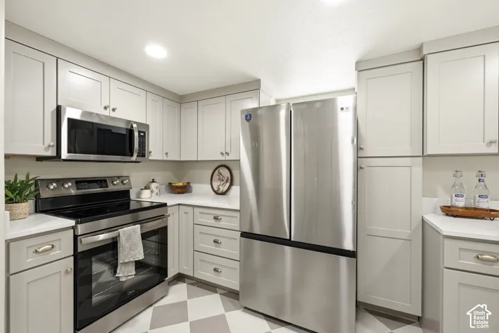 Stainless steel appliances, white countertops, shaker-style cabinetry, recessed lighting, and checkered flooring
