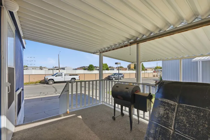 Covered patio with a corrugated roof and white railing