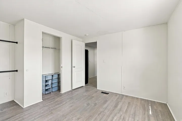 Wood-finish flooring, white paneled walls, and a built-in closet with shelving and hanging rods