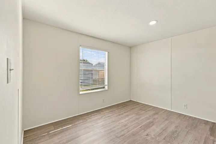 Wood-finish flooring, recessed ceiling lighting, and a window with horizontal blinds