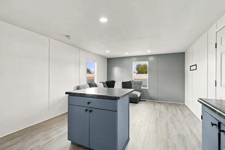 Open-concept living area with recessed lighting, light wood-finish flooring, and a contemporary color palette