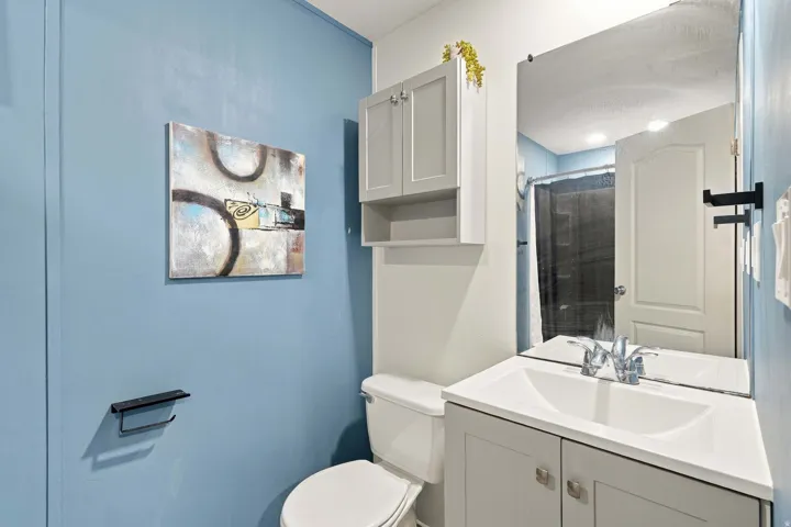 Vanity with undermount sink and chrome faucet, surface-mounted wall mirror, and mounted wall cabinet