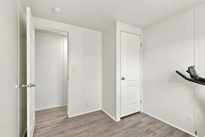 Neutral wall panels, wood-finish flooring, and white interior doors