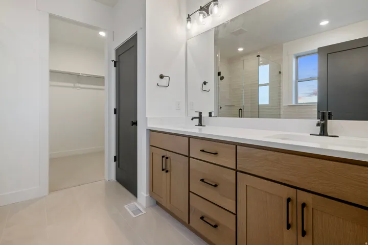Dual vanity with light wood-finish cabinetry, white countertop, and matte black fixtures