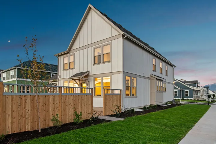 Modern farmhouse-style exterior with vertical siding, gabled roofline, multiple window placements, and a natural wood privacy fence