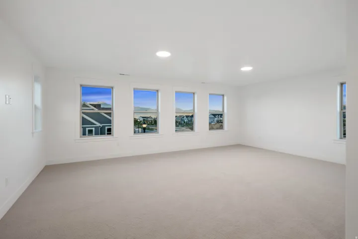Spacious room featuring multiple windows, recessed ceiling lighting, and neutral-toned carpeting