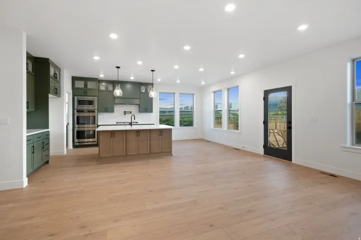 Open-concept kitchen and living area featuring wood-finish flooring, recessed lighting, and ample natural light from multiple windows