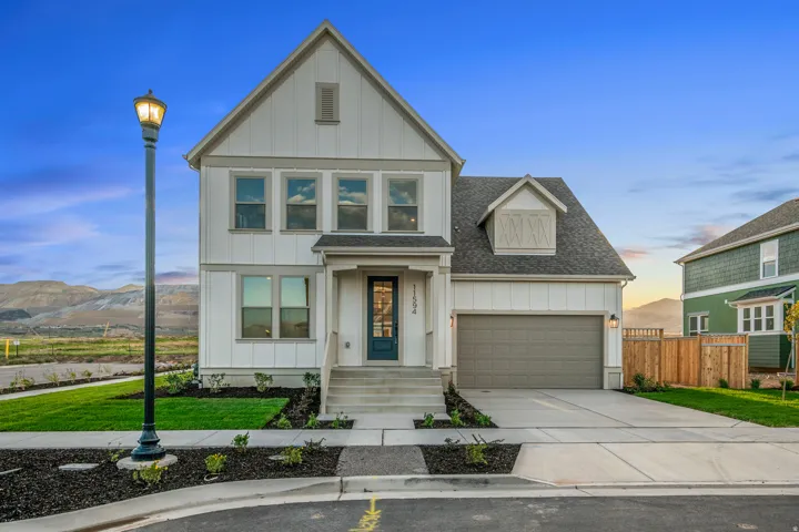 Modern farmhouse exterior with white siding and dark trim, attached two-car garage, concrete driveway, and established landscaping