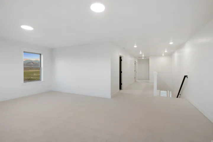 Bright room with recessed lighting, light-toned carpeting, and a window with a mountain backdrop