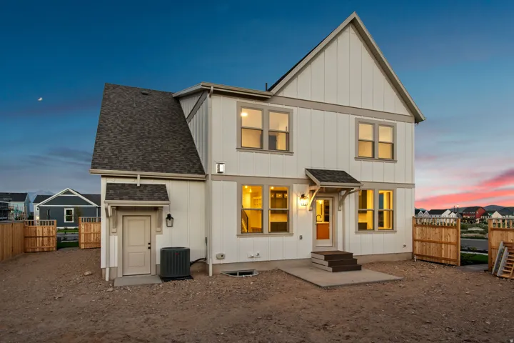 White board and batten siding with gray trim, multiple windows with dark frames, a small covered entry, and a side door with an awning