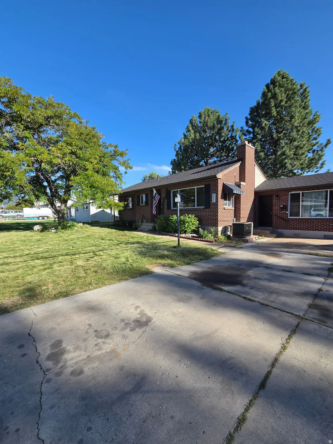 Brick exterior with dark shutters, a prominent chimney, and a concrete driveway