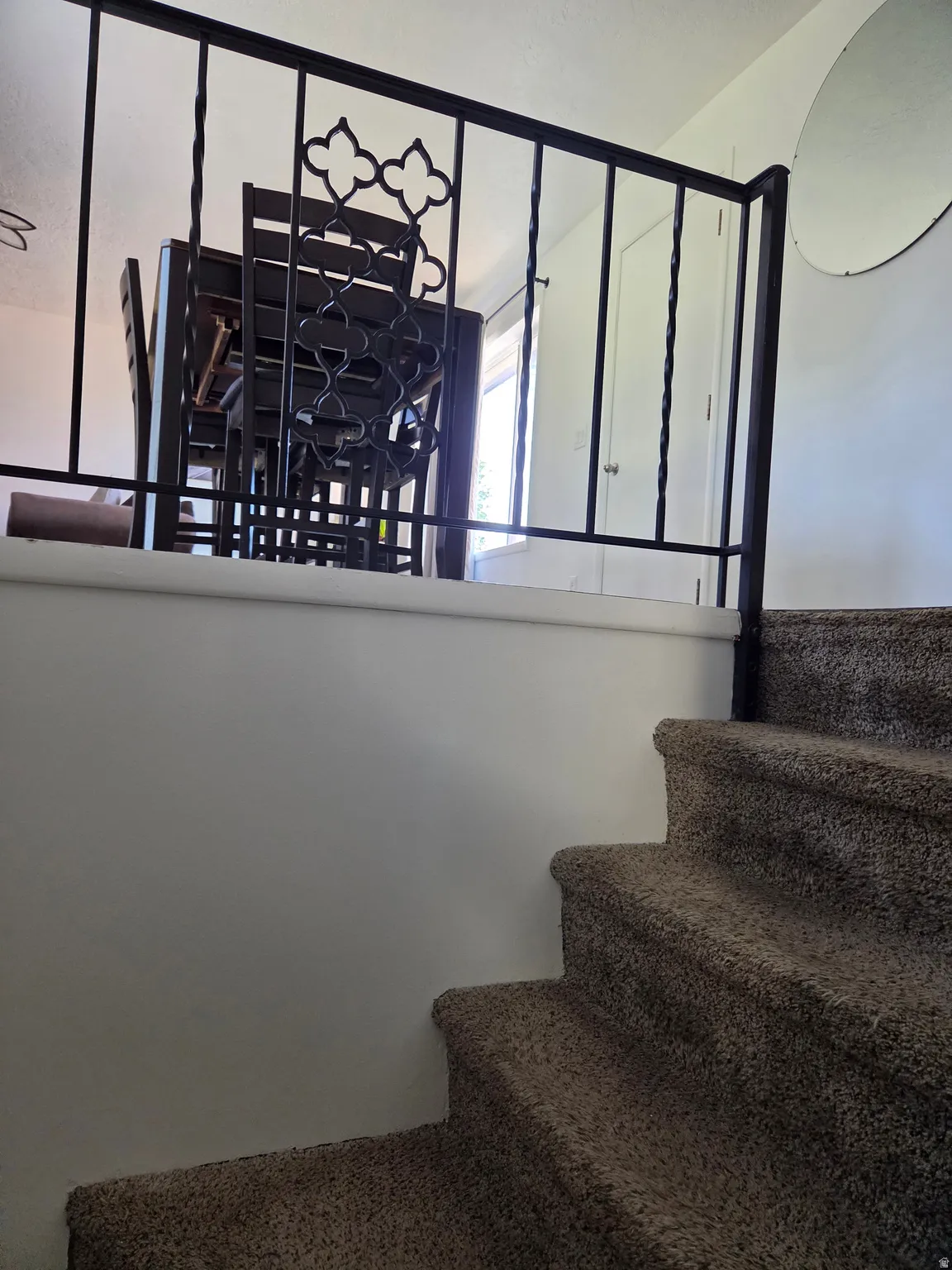 Carpeted staircase with a decorative wrought iron railing