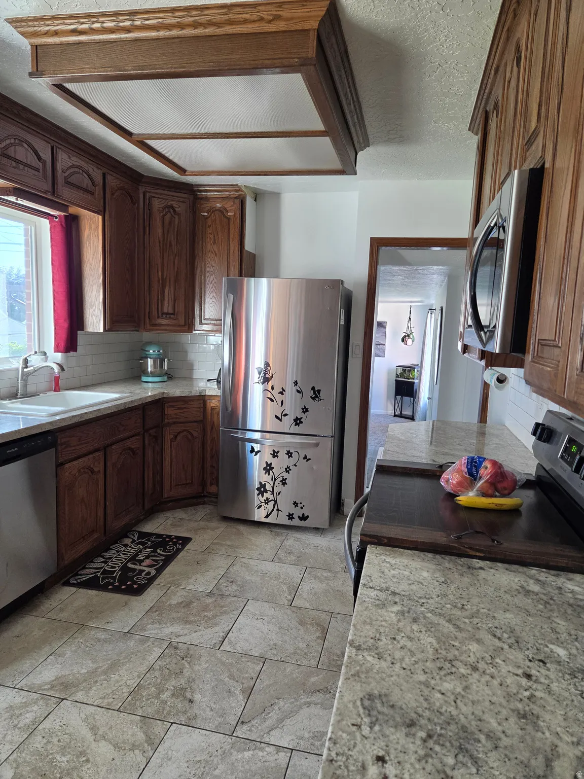 Kitchen featuring wood cabinetry, stainless steel appliances, light-toned tile flooring, and granite counter tops