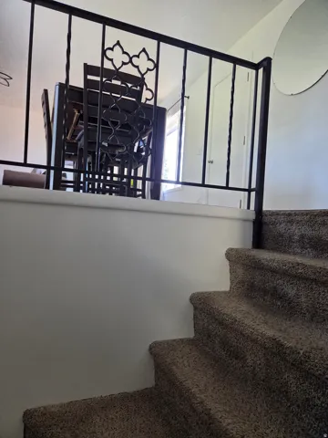Carpeted staircase with a decorative wrought iron railing