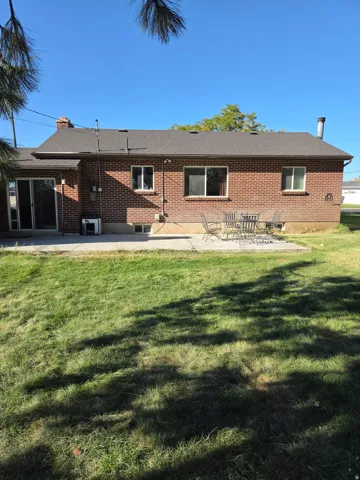 Brick exterior with a shingled roof, a concrete patio, and a sliding glass door
