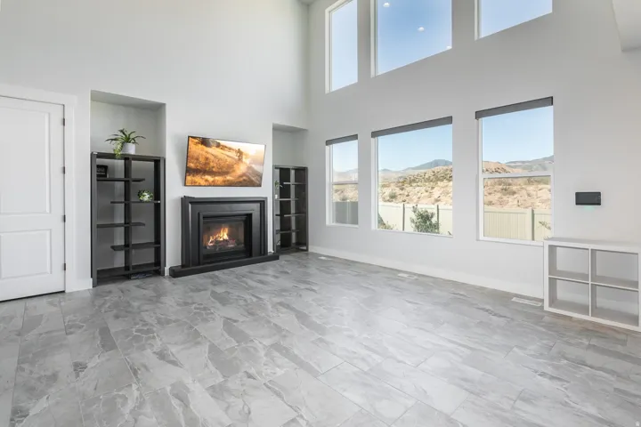 Vaulted ceiling with high windows, built-in fireplace, tile flooring, built-in shelving, and multiple windows