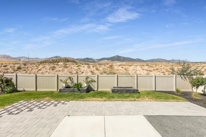 Expansive backyard featuring a manicured lawn, multi-material patio, raised planter boxes, and a built-in fire pit