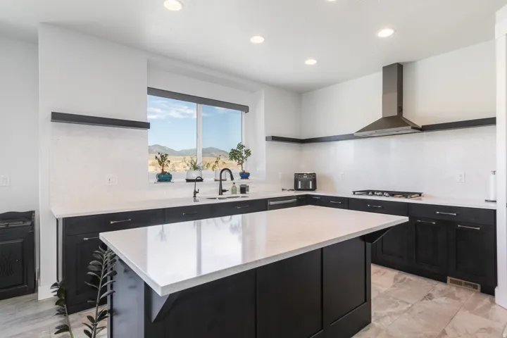 Modern kitchen with a large central island, dark wood-finish cabinetry, light stone countertops, a stainless steel range hood, and recessed lighting