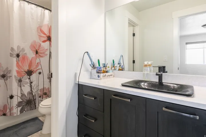 Dark wood-finish vanity with drawer storage, white countertop, rectangular black vessel sink, and matte black faucet