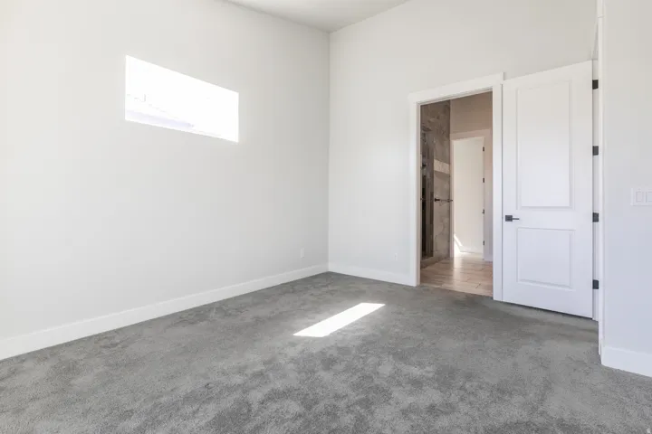 Plush gray carpeting, white painted walls, and a rectangular transom window