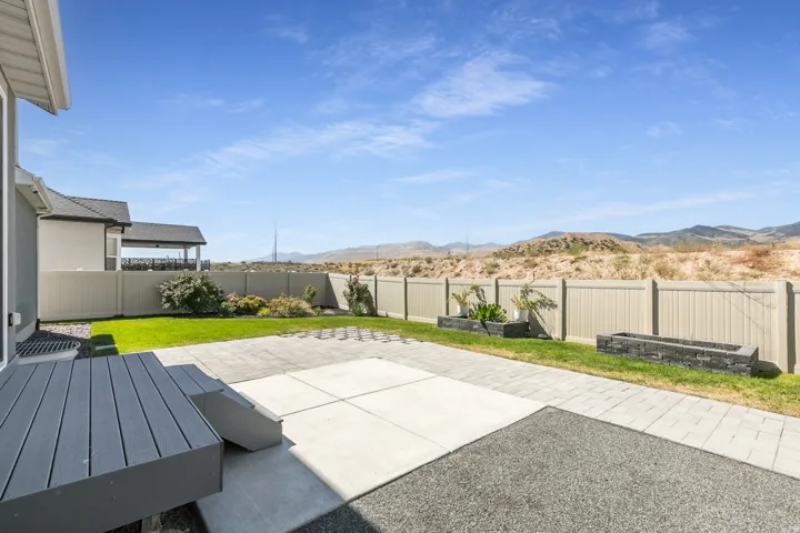 Private backyard featuring a composite deck, concrete patio, paver hardscaping, and a vinyl privacy fence