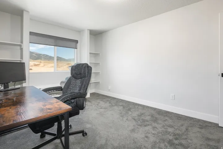Built-in shelving, expansive window, roller shade, textured carpeting, bright white walls