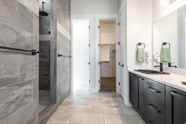 Walk-in shower with full height tile surround, black rainfall shower head, and matte black hardware