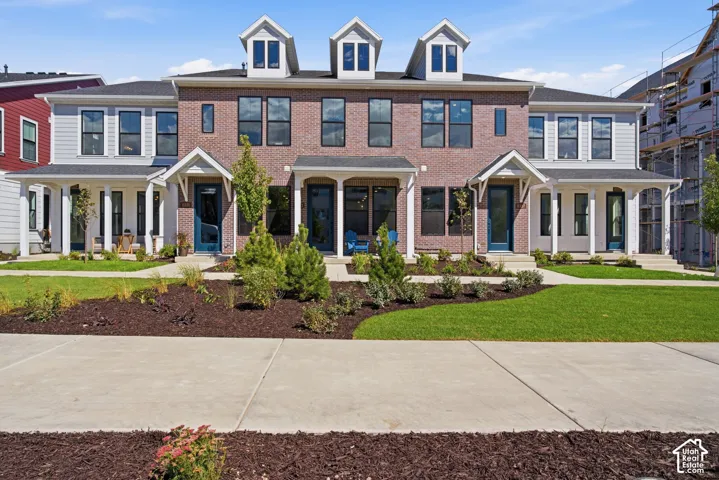 Brick and siding exterior with a covered porch, dormer windows, and a manicured lawn