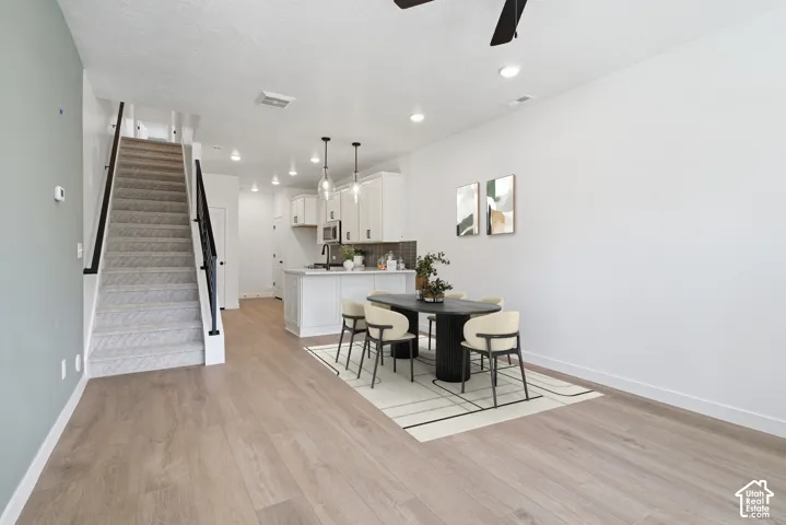 Open-concept living area featuring wood-finish flooring, recessed lighting, and a white kitchen with pendant lighting and an island