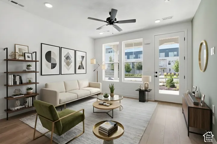 Large windows that let tons of natural light into the family room area, recessed lighting, wood-finish flooring, ceiling fan, and a glass-paneled door