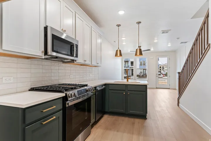 Modern kitchen featuring stainless steel appliances, two-tone cabinetry, and a white tile backsplash