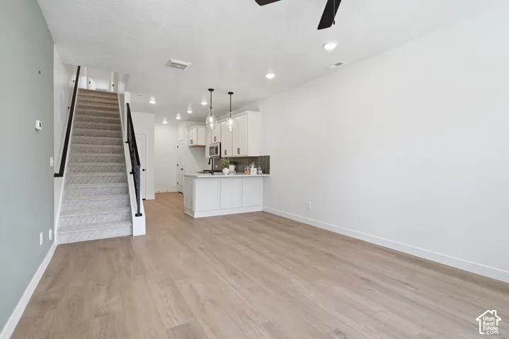 Open-concept living area featuring wood-finish flooring, recessed lighting, and a modern kitchen with white cabinetry