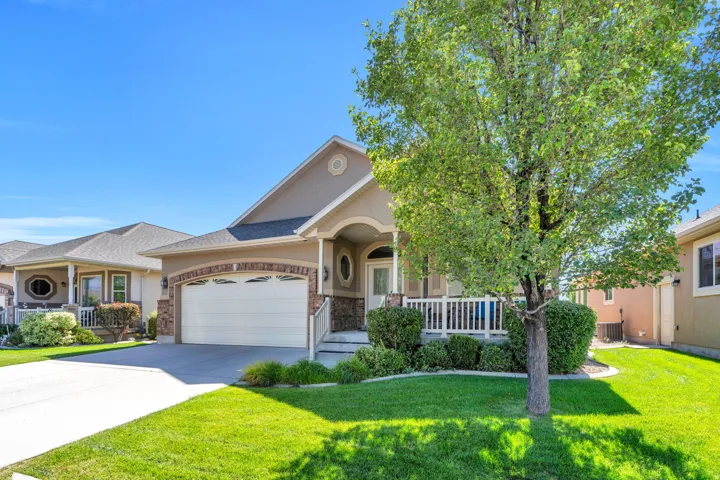 Front view of residence featuring a stucco exterior with stone accents, an arched garage door, and a covered front porch with a white railing