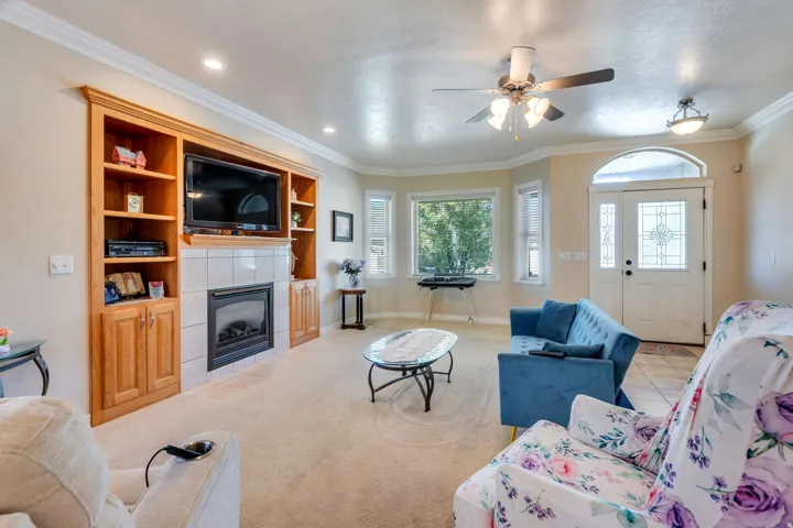 Built-in media center with shelving, tile surround fireplace, and decorative crown molding