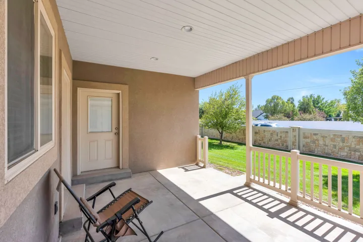 Covered patio with a concrete surface, white railing, and stucco exterior
