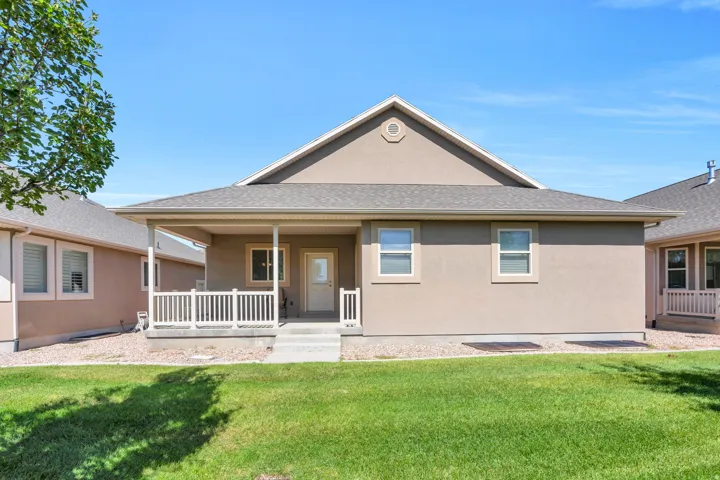 Stucco exterior with a covered porch featuring white railing, concrete steps, and a shingled roof
