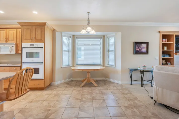 Built-in double ovens, light wood-finish cabinetry, bay window, tile flooring, and integrated shelving unit
