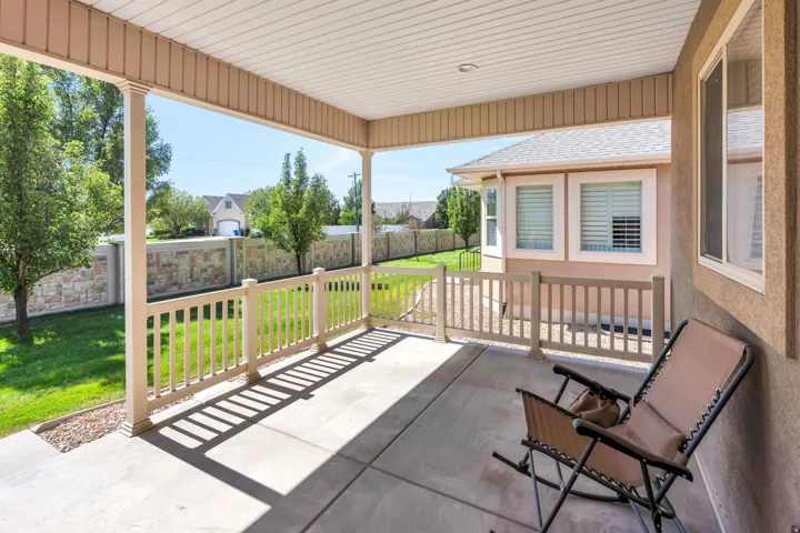 Covered concrete patio with white railing and columns