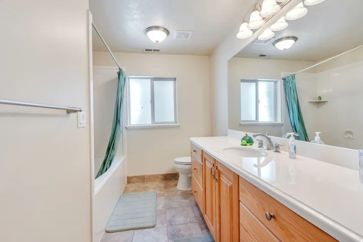 Long vanity with integrated sink, wood-finish cabinetry, and a large mirror