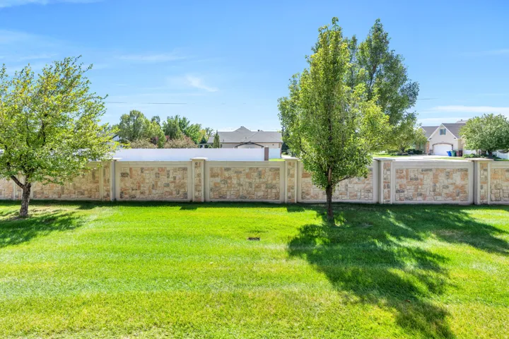 Expansive lawn area with mature trees and a stone-accented perimeter wall