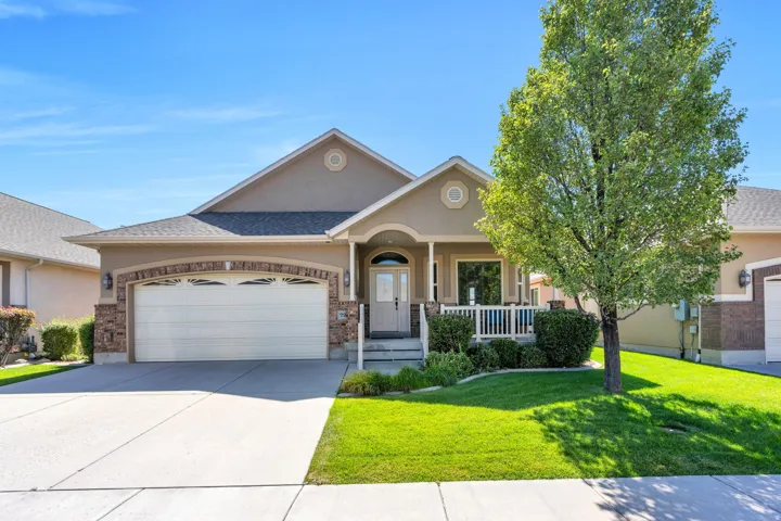 Stucco and stone exterior with a two-car garage, covered porch, and front yard landscaping